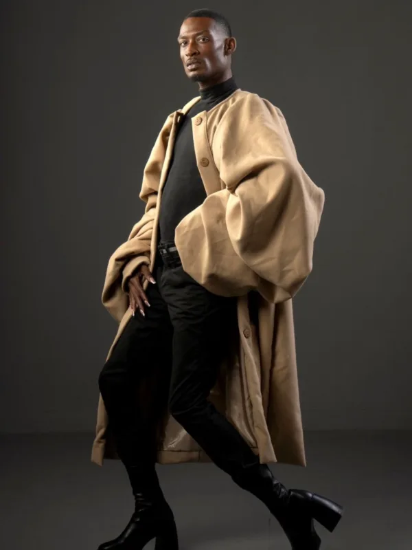 Model in an oversized camel wool coat with voluminous balloon sleeves and wooden buttons, worn over a black turtleneck