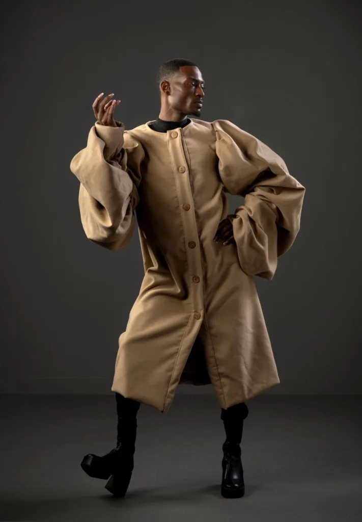 Model in an oversized camel wool coat with voluminous balloon sleeves and wooden buttons, worn over a black turtleneck